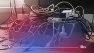 Tangled cables and power strips on a desk representing disconnected and unmanaged IT systems