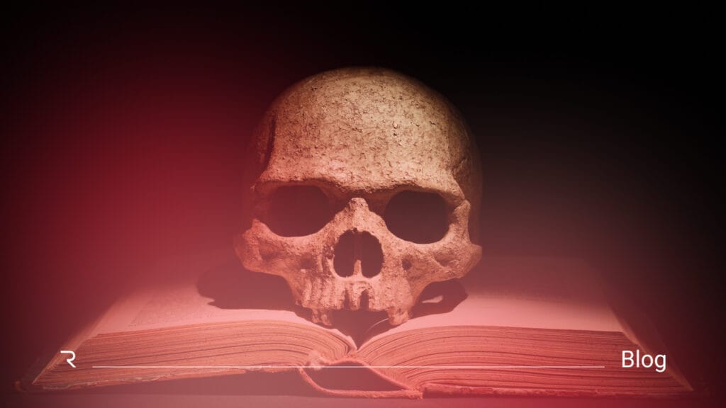 Skull resting on open book with red atmospheric lighting representing identity security threats and risks
