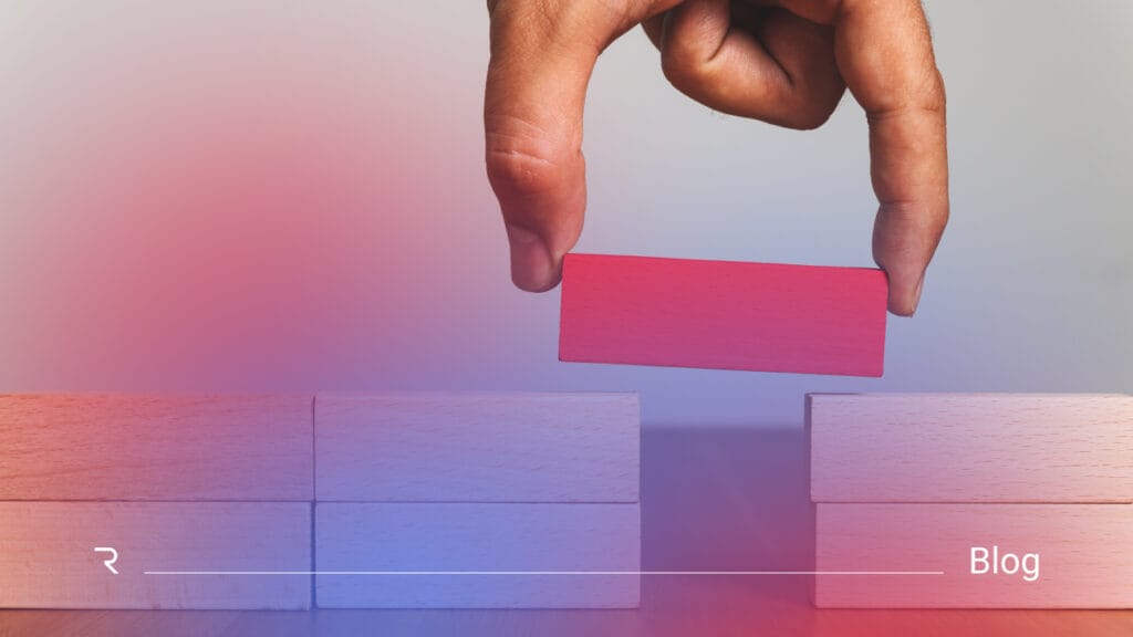Hand placing a wooden block to bridge a gap between two structures, symbolizing connecting identity systems and closing security gaps.